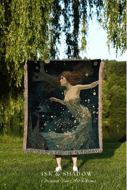 May include: A dark blue throw blanket featuring a woman with flowing auburn hair and a flowing gown, with gold accents. The artwork has a dreamy, ethereal quality. The blanket has a fringed edge and the text "INK & SHADOW Original Fine Art Throws".