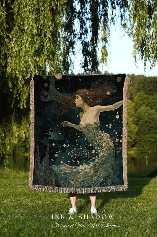 May include: A dark blue throw blanket featuring a woman with flowing auburn hair and a flowing gown, with gold accents. The artwork has a dreamy, ethereal quality. The blanket has a fringed edge and the text "INK & SHADOW Original Fine Art Throws".