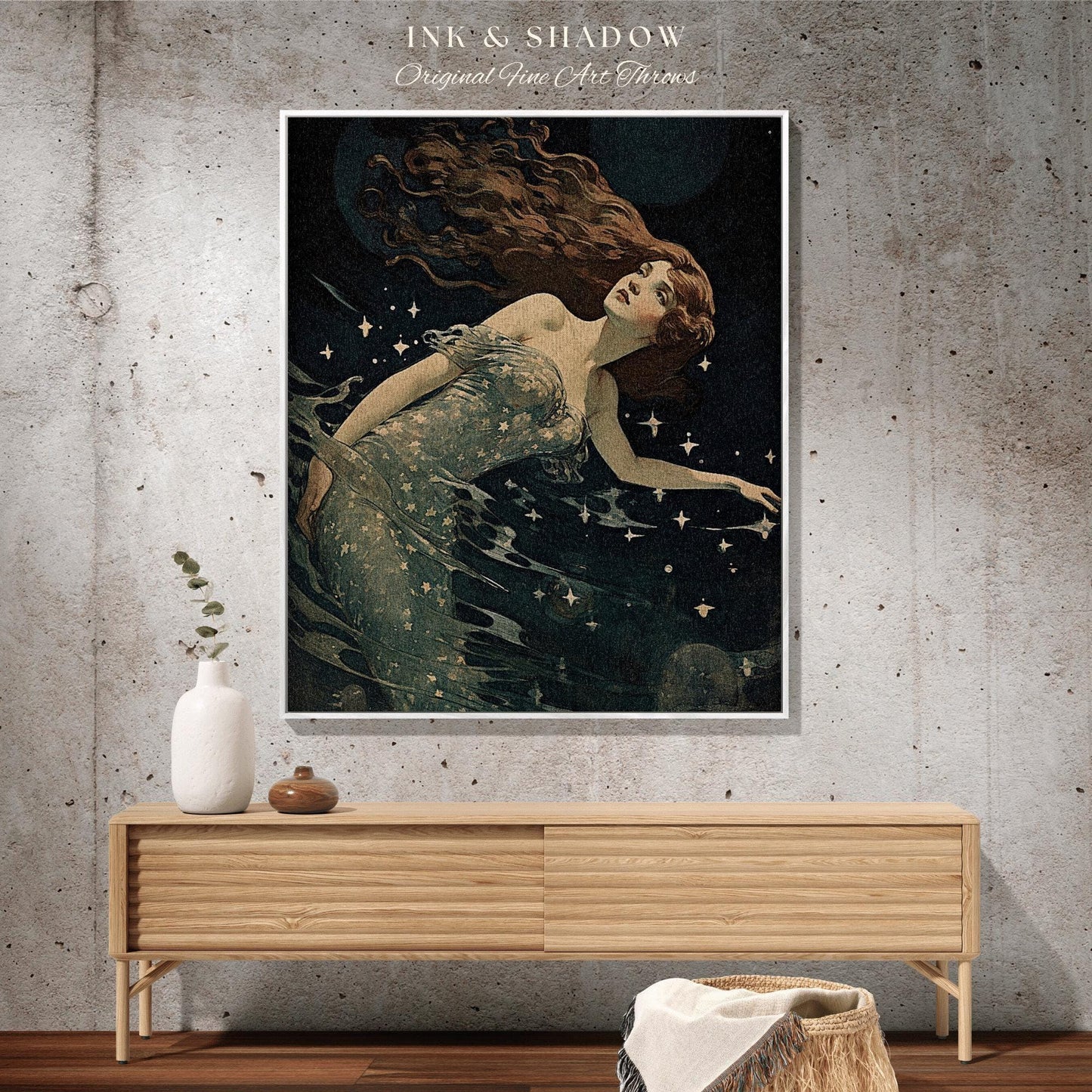 May include: A framed art print featuring a vintage illustration of a woman with long auburn hair, floating in dark water with stars. The artwork is titled "INK & SHADOW Original Fine Art Throws". The print is displayed above a wooden cabinet.