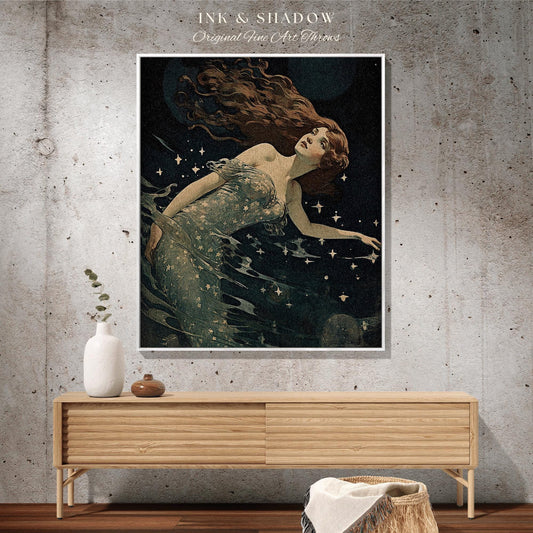 May include: A framed art print featuring a vintage illustration of a woman with long auburn hair, floating in dark water with stars. The artwork is titled "INK & SHADOW Original Fine Art Throws". The print is displayed above a wooden cabinet.