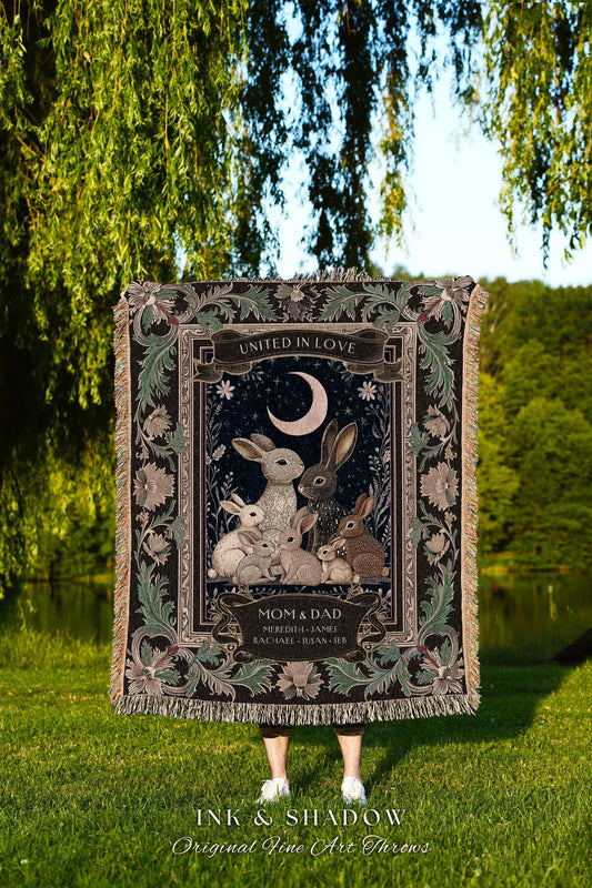 May include: A decorative throw blanket featuring a family of rabbits under a crescent moon, with the words "United in Love" at the top. The blanket has a dark background with floral accents and the text "Mom & Dad". The bottom reads "Ink & Shadow".