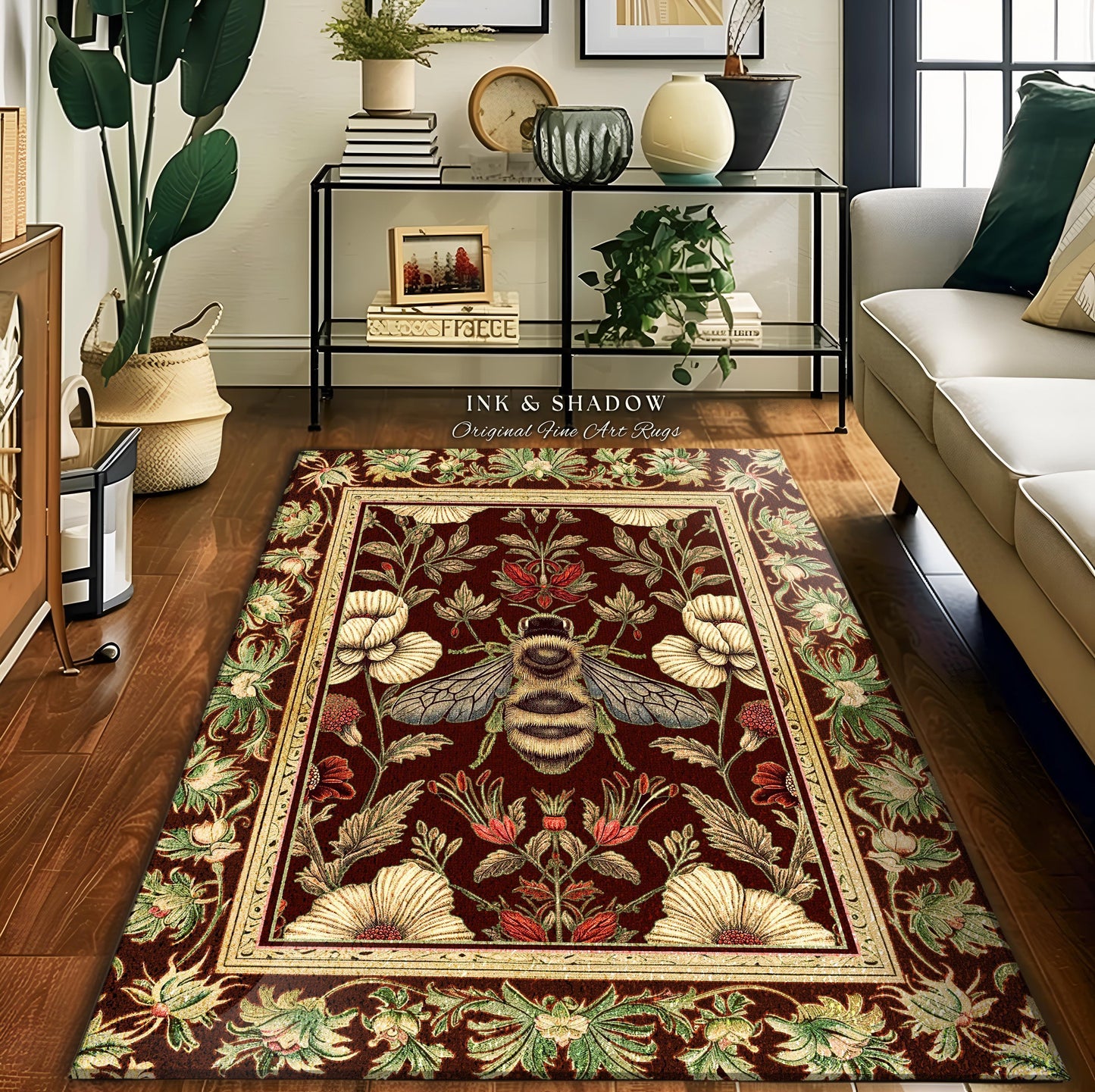 May include: A rectangular area rug with a burgundy background and a detailed floral and bee design. The rug features a cream-colored border and the text "INK & SHADOW Original Fine Art Rugs".