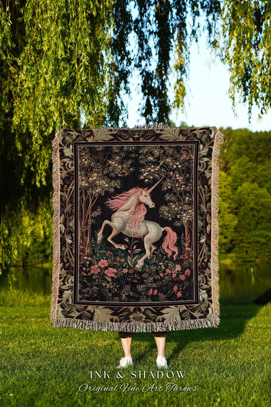 May include: A tapestry throw blanket featuring a unicorn in a forest scene with pink flowers and a black background. The blanket has a decorative border and fringe. The text "INK & SHADOW Original Fine Art Throws" is at the bottom.