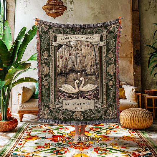 May include: A decorative green throw blanket featuring a romantic scene with two swans on a lake, framed by floral and scrollwork borders. The text "FOREVER & ALWAYS" and "DYLAN & GABBY 2024" are displayed. The blanket has a fringed edge.