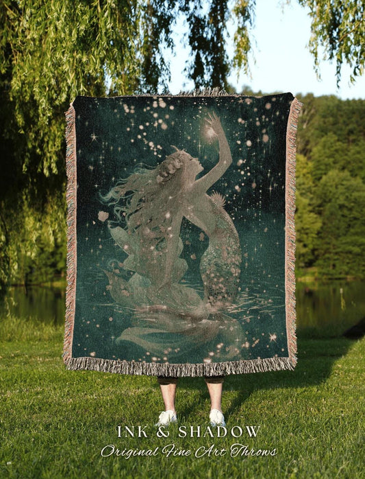 May include: A dark teal throw blanket featuring a mermaid design with a starry night sky background. The mermaid is reaching for a glowing light. The blanket has a fringed edge and the text "INK & SHADOW Original Fine Art Throws" is visible at the bottom.
