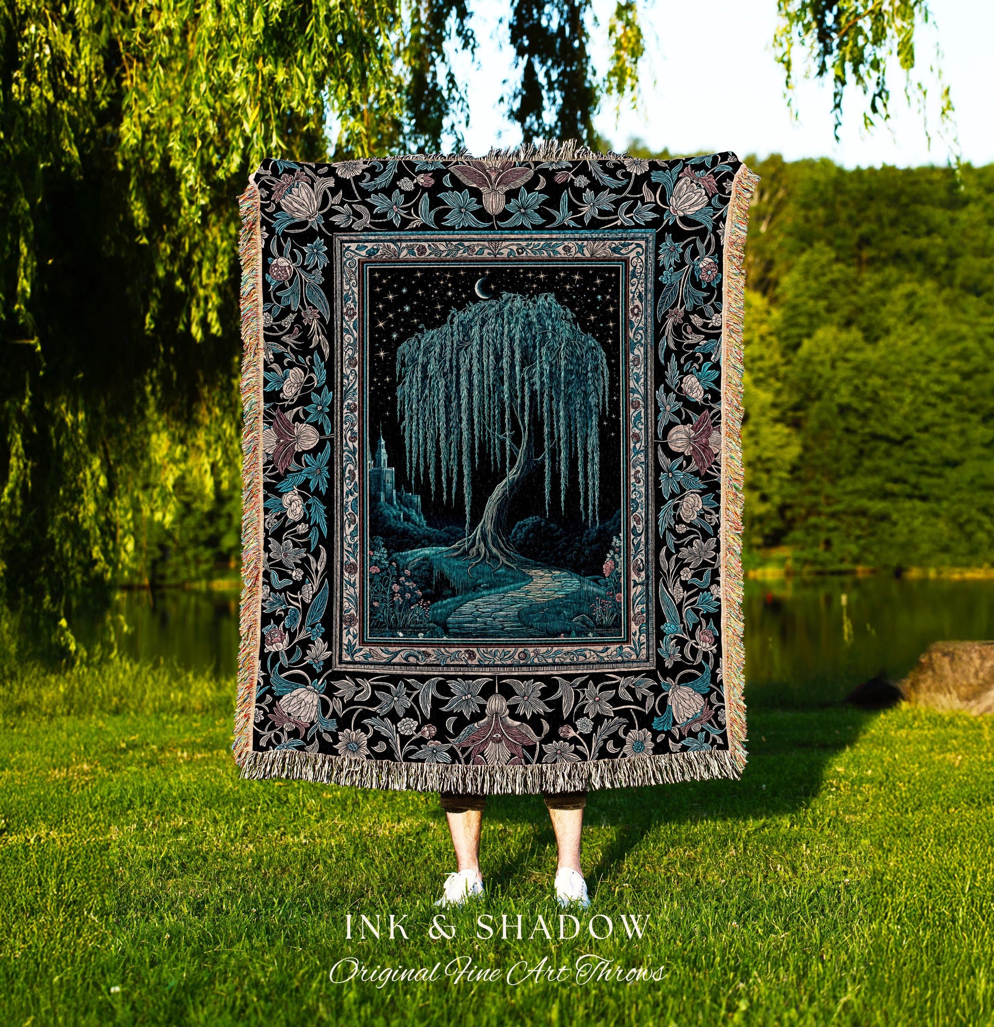 May include: A woven tapestry throw blanket with a black background and a detailed floral border. The center of the blanket features a dark blue willow tree with a crescent moon above it. The tree is surrounded by a dark blue path and a castle in the distance. The text 'INK & SHADOW Original Fine Art Throws' is printed below the blanket.