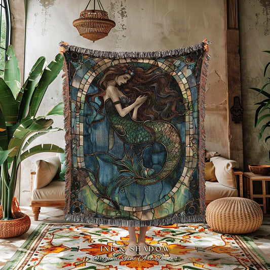 May include: A woven throw blanket featuring a mermaid design in shades of blue, green, and brown. The mermaid is depicted with long flowing hair and a detailed tail. The blanket has a fringed edge and the text "INK & SHADOW Original Fine Art Throws".