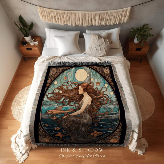 May include: A decorative throw blanket featuring an art nouveau style illustration of a mermaid with long flowing auburn hair. The mermaid is seated in the ocean with fish and stars. The blanket has a black border and the text "INK & SHADOW Original Fine Art Throws".