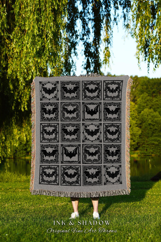 May include: A black and gray woven throw blanket with a repeating pattern of bats in ornate frames. The blanket has a fringe border and the text 'INK & SHADOW Original Fine Art Throws' is printed at the bottom.