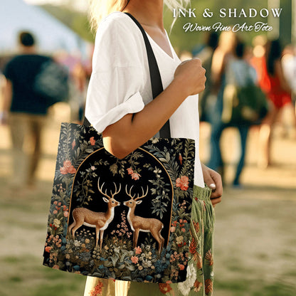 May include: A black tote bag with a floral design and two deer in a forest scene. The bag has the text "INK & SHADOW Woven Fine Art Tote" printed on it.