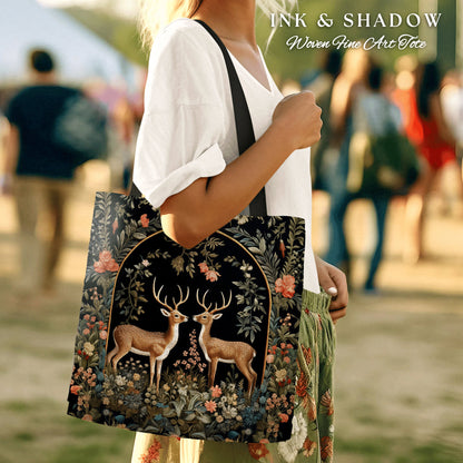 May include: A black tote bag with a floral design and two deer in a forest scene. The bag has the text "INK & SHADOW Woven Fine Art Tote" printed on it.