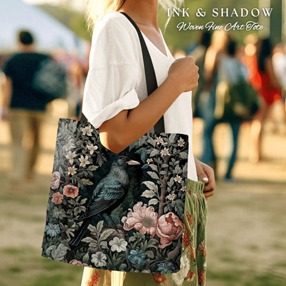 May include: A black tote bag with a woven design featuring a dark blue bird perched on a branch with pink and white flowers. The bag has the text "INK & SHADOW Woven Fine Art Tote" printed on the top.