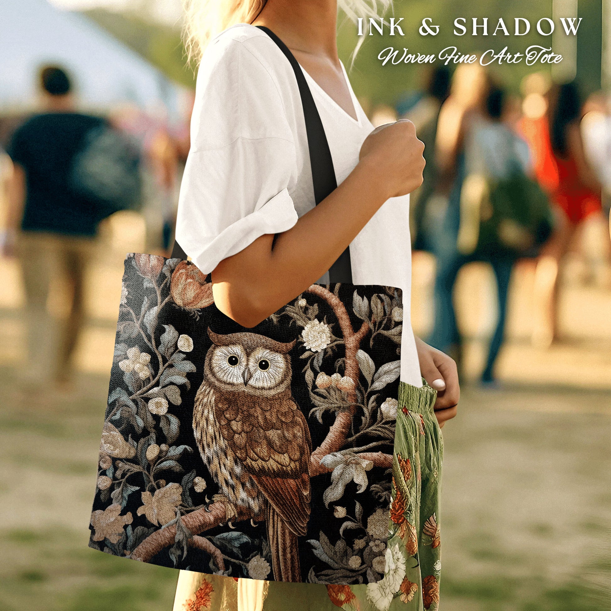May include: A black tote bag with a woven tapestry design featuring an owl perched on a branch with flowers and leaves. The text "INK & SHADOW Woven Fine Art Tote" is printed on the bag.