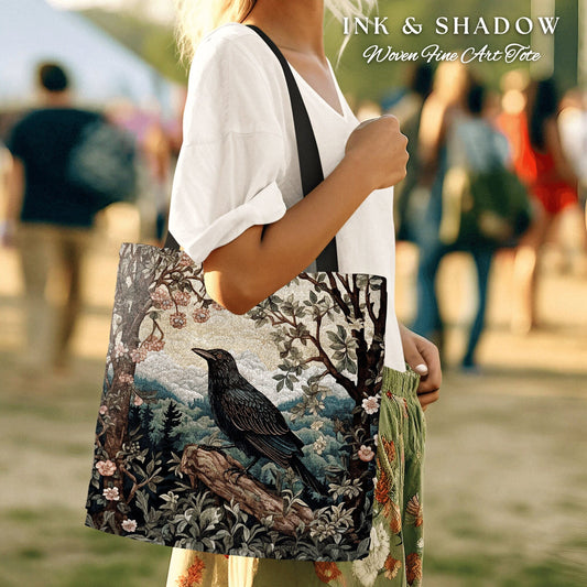May include: A black tote bag with a woven tapestry design featuring a black raven perched on a branch in a forest setting. The bag has a black strap and the text "INK & SHADOW Woven Fine Art Tote" is printed on the top.