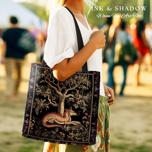 May include: A black tote bag with a woven tapestry design featuring a dragon and a tree. The tapestry is in shades of gold, green, and red. The bag has black straps and the text "INK & SHADOW Woven Fine Art Tote" is printed on the top.