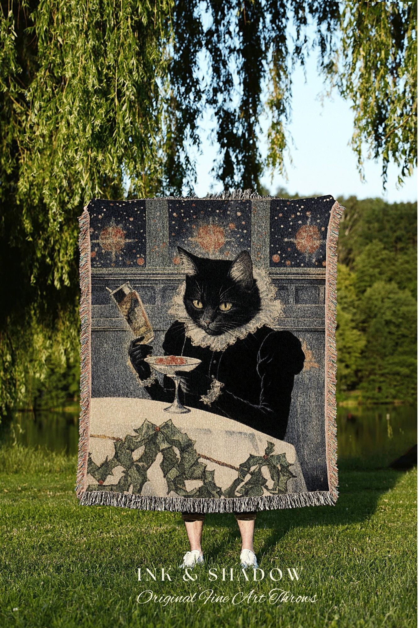 May include: A tapestry throw blanket featuring a black cat dressed in Renaissance attire, holding a drink and a book. The blanket has a fringed edge and a starry background. The text "INK & SHADOW Original Fine Art Throws" is at the bottom.