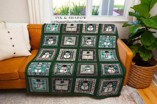 May include: A green and white patchwork throw blanket featuring a repeating pattern of snowmen in square frames. The blanket is draped over a brown leather couch. The blanket has the text "INK & SHADOW Original Fine Art Throws".