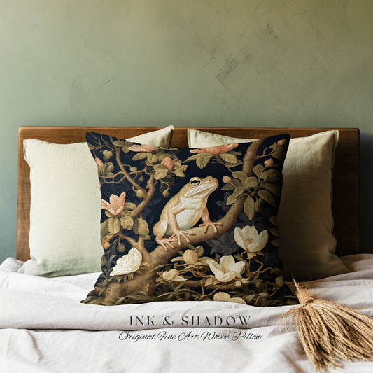 May include: A black and gold woven pillow with a white frog sitting on a branch with white flowers. The pillow has the text "INK & SHADOW Original Fine Art Woven Pillow" printed on the bottom.