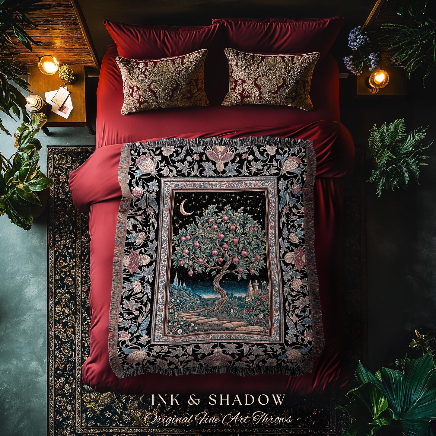 May include: A decorative throw blanket with a detailed tree and night sky design, featuring a crescent moon and stars. The blanket is framed by a floral border and fringed edges. The text "INK & SHADOW Original Fine Art Throws" is at the bottom. The blanket is on a red bed.