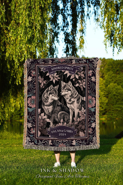 May include: A woven throw blanket featuring a detailed illustration of two wolves facing each other, surrounded by floral elements. The blanket has a dark purple border with the text "Kindred Spirits" and "Dylan & Gabby 2024". The bottom of the blanket has the text "INK & SHADOW Original Fine Art Throws".