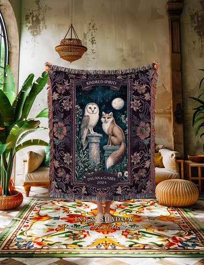 May include: A dark purple woven throw blanket featuring an owl and fox design with the words "Kindred Spirits" and "Dylan & Gabby 2024". The blanket has a fringed edge and a floral border. The blanket is approximately 60 inches wide and 80 inches long.