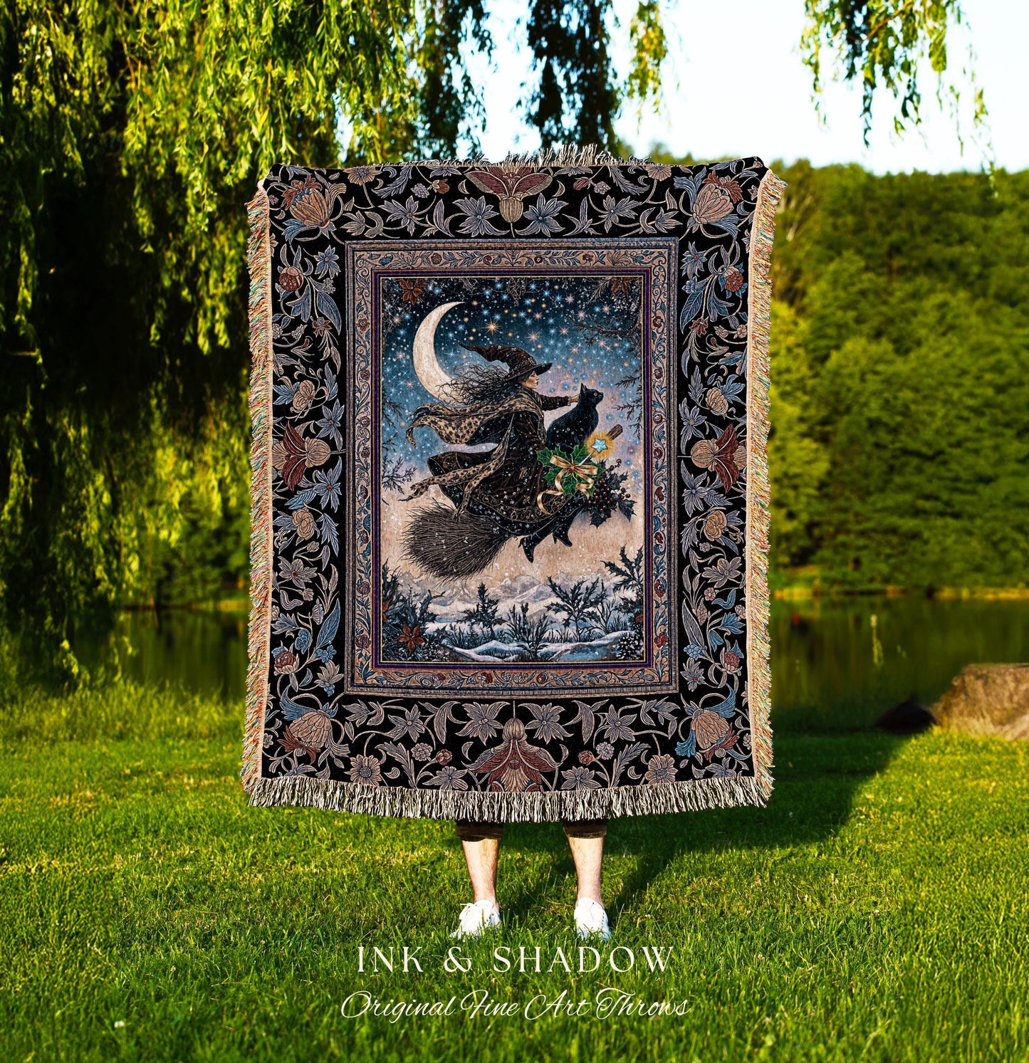 May include: A decorative throw blanket featuring a witch flying on a broomstick with a black cat under a crescent moon and starry sky. The blanket has a black floral border and fringe. The text "INK & SHADOW Original Fine Art Throws" is at the bottom.