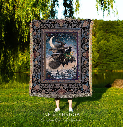May include: A decorative throw blanket featuring a witch flying on a broomstick with a black cat under a crescent moon and starry sky. The blanket has a black floral border and fringe. The text "INK & SHADOW Original Fine Art Throws" is at the bottom.