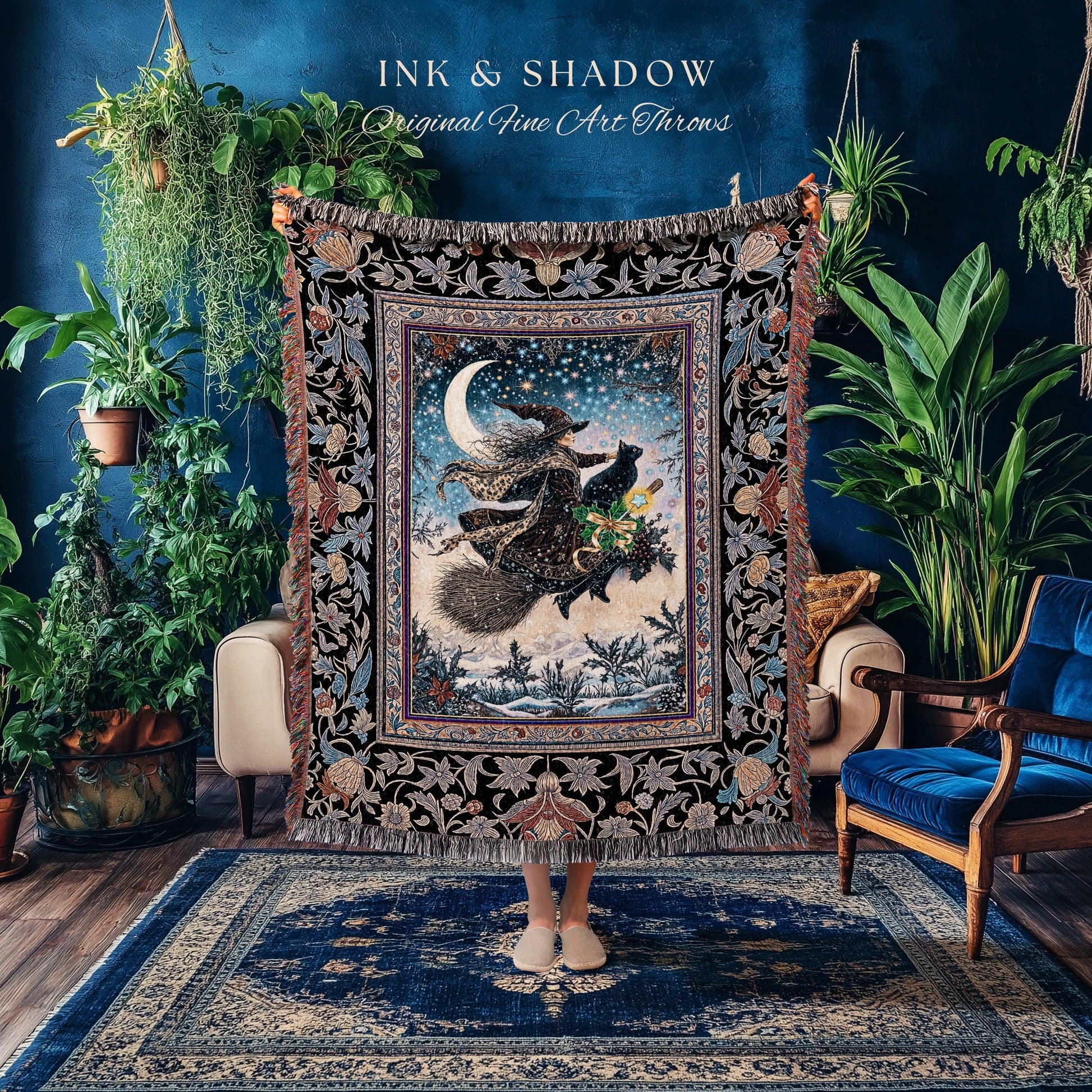 May include: A decorative throw blanket featuring a witch on a broomstick with a black cat, flying in front of a crescent moon and starry sky. The blanket has a black floral border and the text "INK & SHADOW Original Fine Art Throws".