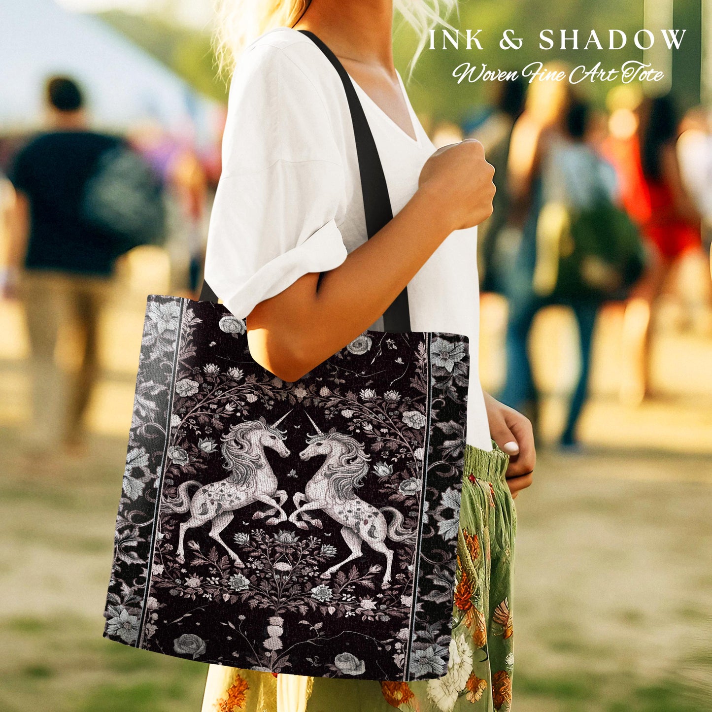 May include: A black tote bag with a woven tapestry design featuring two white unicorns in a floral setting. The text "INK & SHADOW Woven Fine Art Tote" is printed on the bag.