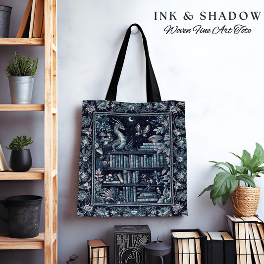 May include: A blue and white tote bag with a woven design featuring a dragon, books, and a moon. The text "INK & SHADOW Woven Fine Art Tote" is printed on the bag.
