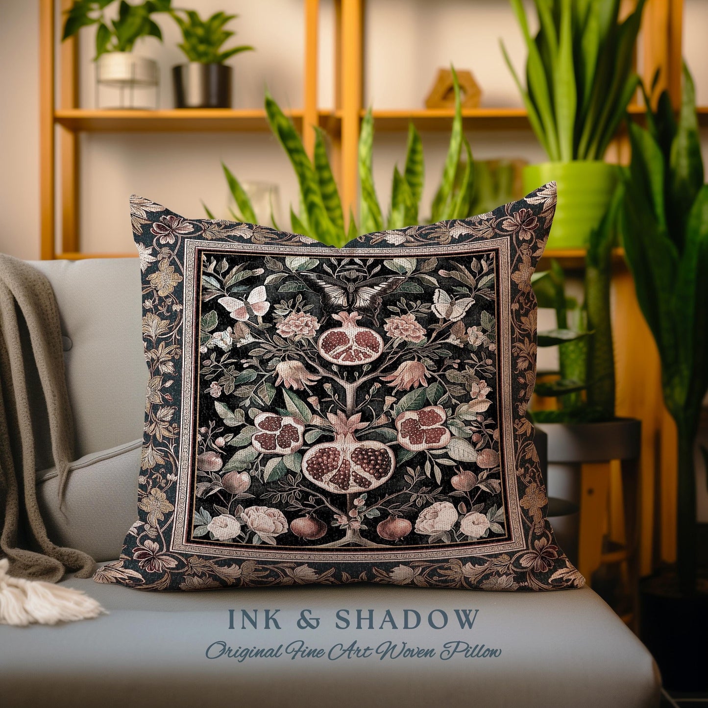 May include: A decorative throw pillow with a woven tapestry design featuring a pomegranate tree with intricate details. The pillow is black with shades of pink, green, and gold. The text "INK & SHADOW Original Fine Art Woven Pillow" is printed on the bottom of the pillow.
