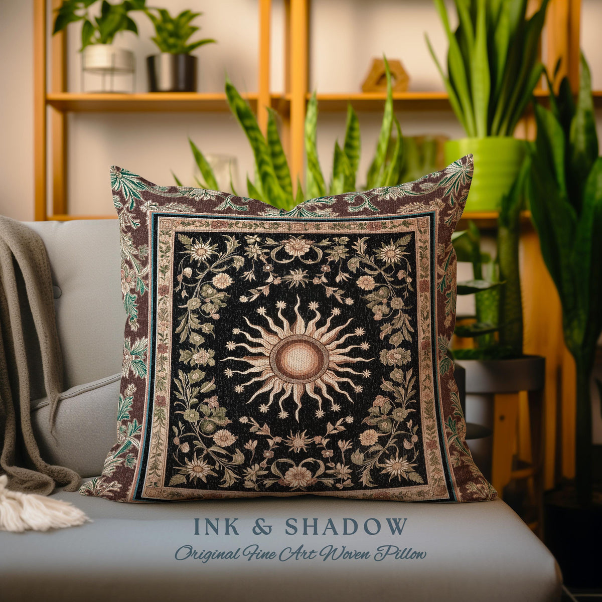 May include: A decorative throw pillow with a woven tapestry design featuring a sun with rays and floral patterns in shades of brown, green, and cream. The pillow has a black background and the text "INK & SHADOW Original Fine Art Woven Pillow" is printed on the bottom.