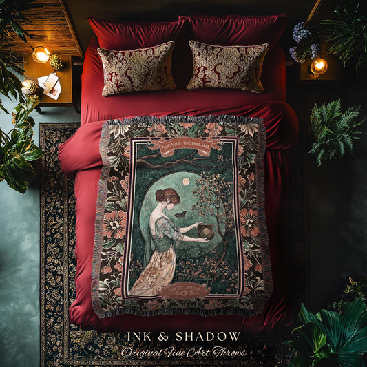 May include: A decorative throw blanket with a vintage art print featuring a woman in a garden scene. The blanket has a dark border with floral patterns and the text "INK & SHADOW Original Fine Art Throws". The bed has red bedding and decorative pillows.
