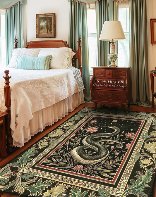 May include: A rectangular black rug with a detailed design featuring a snake, flowers, and foliage. The rug has a red and gold border, with the text "INK & SHADOW Original Fine Art Rugs" on a nearby wooden cabinet.