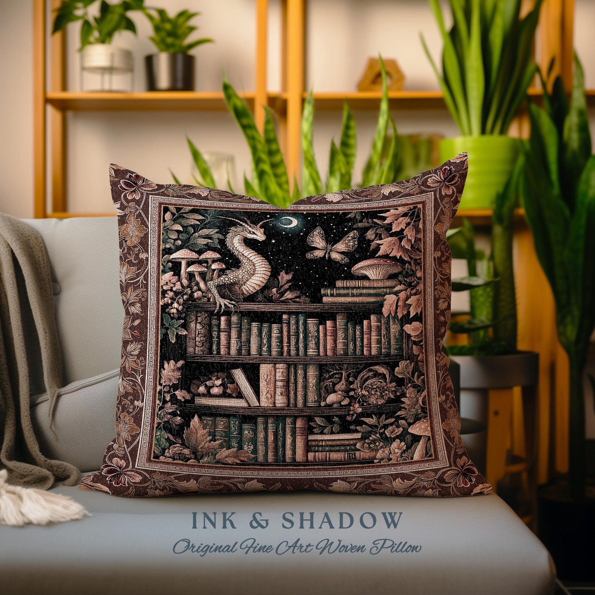 May include: A decorative pillow with a tapestry-style design featuring a dragon, a bookshelf filled with books, and a moon and stars. The pillow has a brown background with gold accents and the text "Ink & Shadow Original Fine Art Woven Pillow".