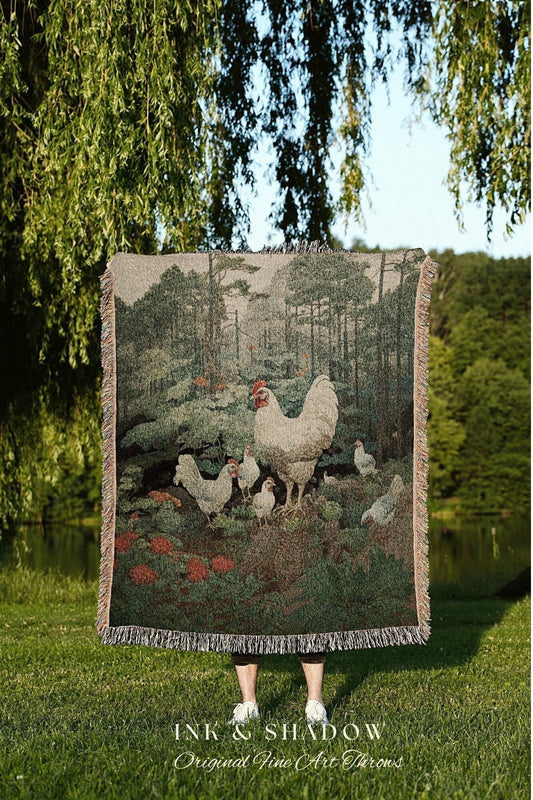 May include: A woven tapestry throw blanket featuring a pastoral scene with chickens and a forest backdrop. The blanket has a fringed edge and is primarily green, brown, and beige. The text "INK & SHADOW Original Fine Art Throws" is at the bottom.