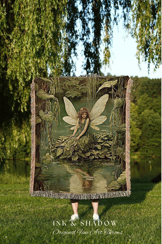 May include: A tapestry throw blanket featuring a fairy in a forest scene with a waterfall and a pond. The artwork is in shades of green and brown, with a fringe border. The text "INK & SHADOW Original Fine Art Throws" is at the bottom.