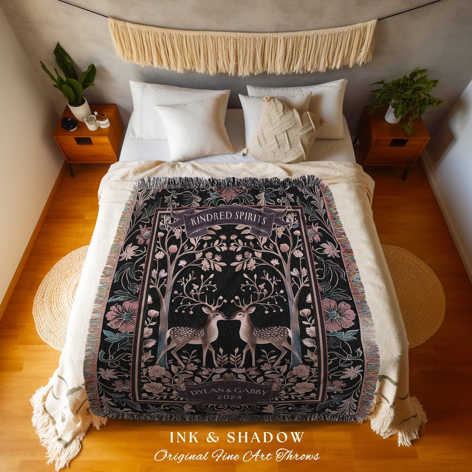 May include: A black throw blanket with a floral and deer design. The blanket features the text "Kindred Spirits" and "Dylan & Gabby 2024". The blanket is fringed and has a decorative border with pink and teal accents.