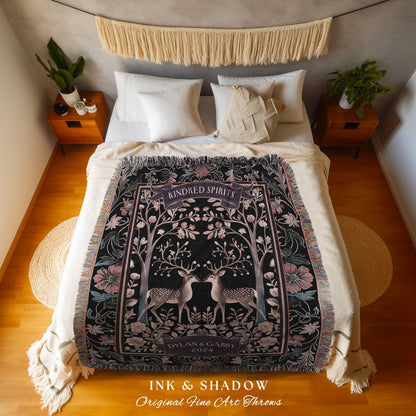 May include: A black throw blanket with a floral and deer design. The blanket features the text "Kindred Spirits" and "Dylan & Gabby 2024". The blanket is fringed and has a decorative border with pink and teal accents.