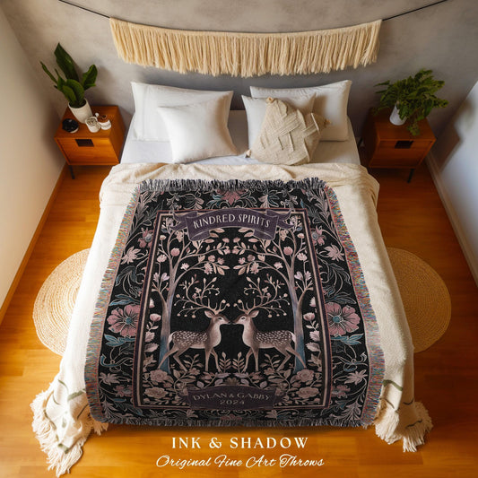 May include: A black throw blanket with a floral and deer design. The blanket features the text "Kindred Spirits" and "Dylan & Gabby 2024". The blanket is fringed and has a decorative border with pink and teal accents.
