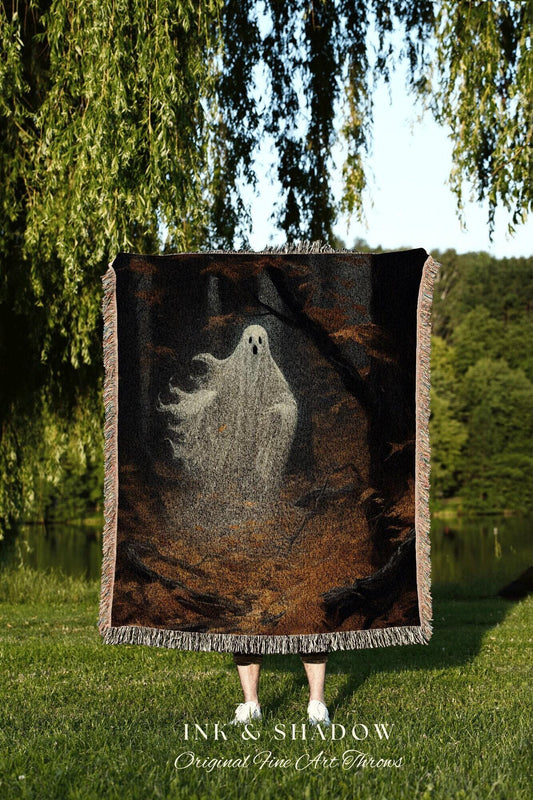 May include: A woven throw blanket featuring a ghostly figure in a dark forest scene. The blanket has a black background with brown and gray accents, and a fringe border. The text "INK & SHADOW Original Fine Art Throws" is at the bottom.