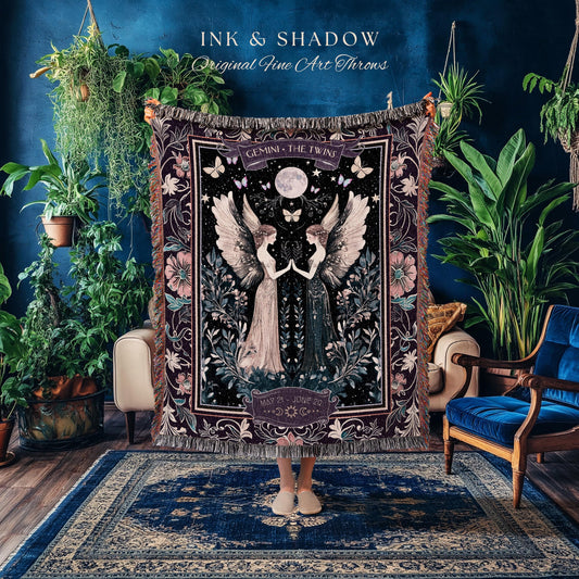 May include: A decorative throw blanket with a celestial design featuring two winged figures, butterflies, and a full moon. The blanket is dark with floral and astrological details, and the text "INK & SHADOW Original Fine Art Throws" is visible.