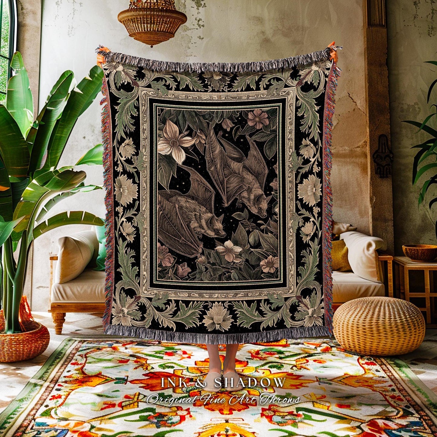 May include: A black and beige woven throw blanket featuring a detailed illustration of bats, flowers, and foliage. The blanket has a decorative border and fringe. The text "INK & SHADOW Original Fine Art Throws" is visible at the bottom.