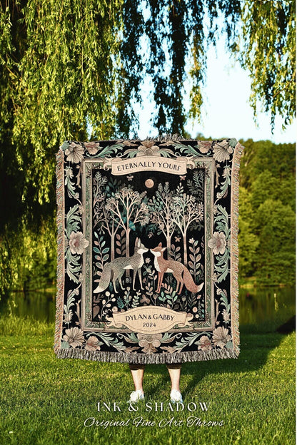 May include: A black tapestry throw blanket with a forest scene featuring two foxes, trees, and floral elements. The blanket has a fringed edge and the text "Eternally Yours" and "Dylan & Gabby 2024". The blanket is displayed outdoors.