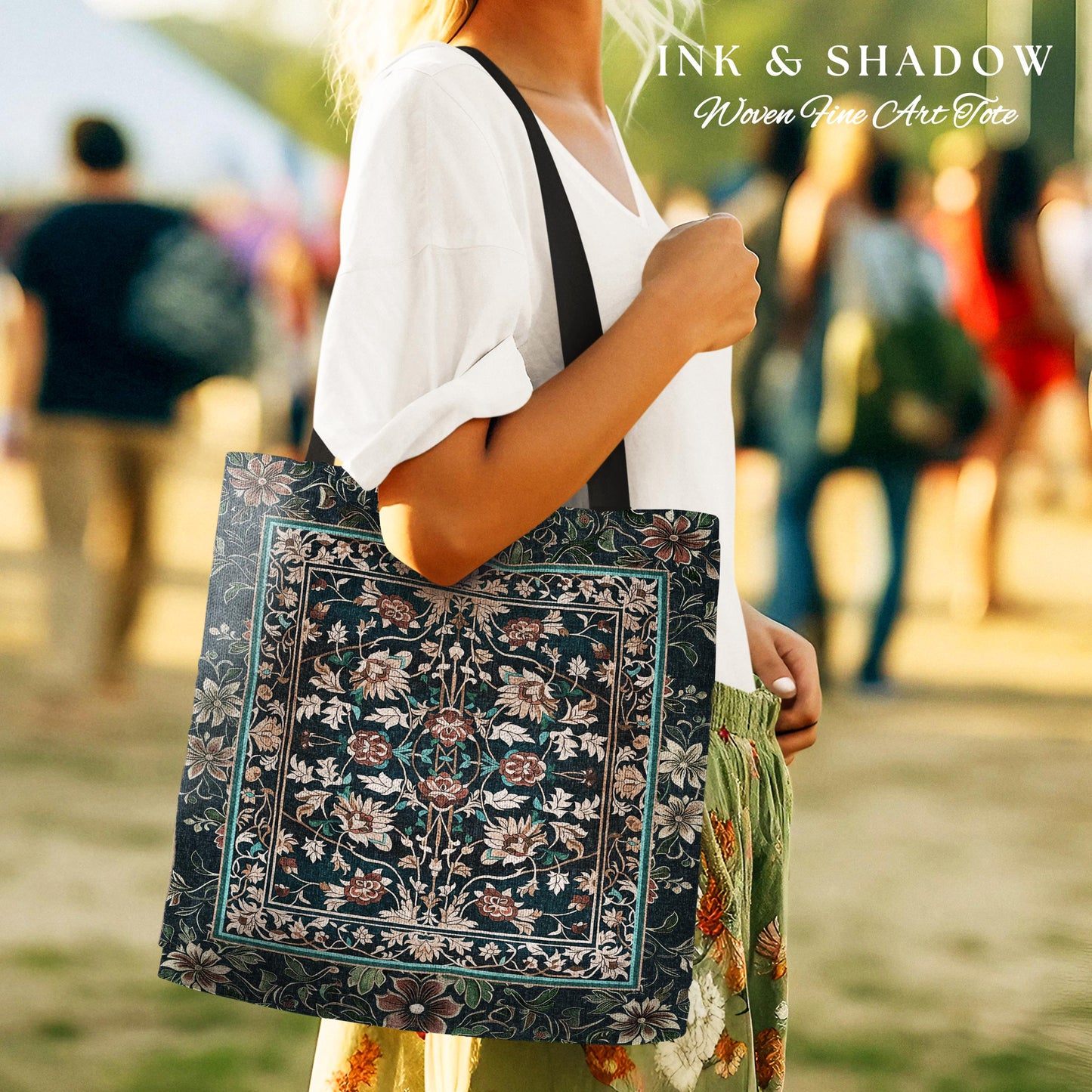 May include: A black tote bag with a woven floral pattern in shades of green, pink, and white. The bag has black straps and the text "INK & SHADOW Woven Fine Art Tote" is printed on the top.