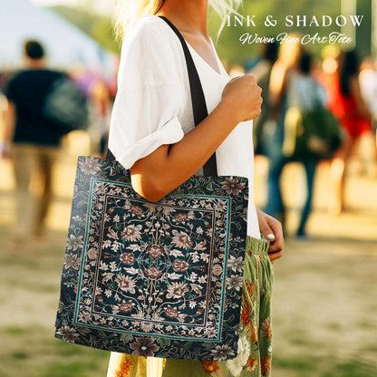 May include: A black tote bag with a woven floral pattern in shades of green, pink, and white. The bag has black straps and the text "INK & SHADOW Woven Fine Art Tote" is printed on the top.