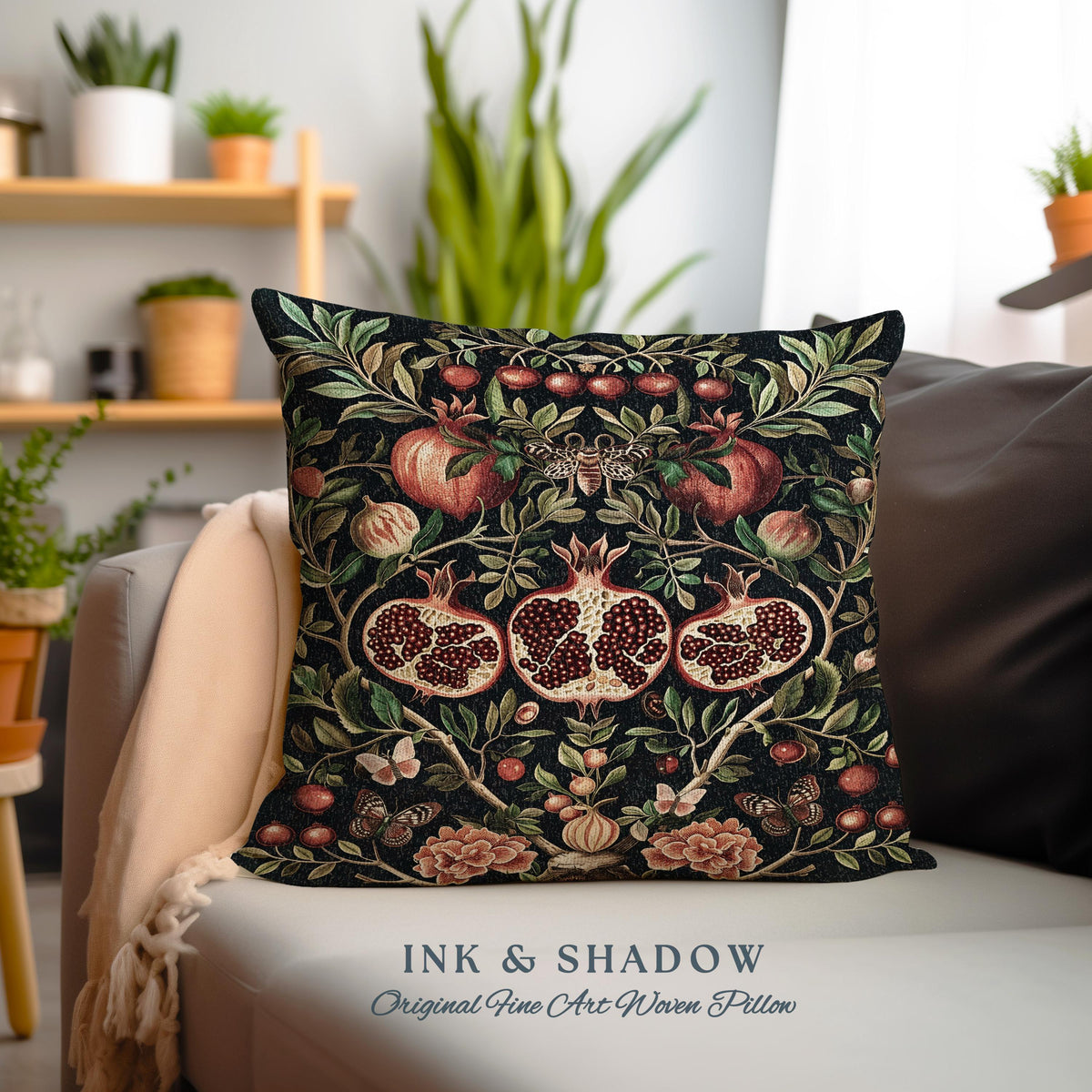 May include: A black throw pillow with a woven design featuring red pomegranates, green leaves, and butterflies. The pillow has the text "INK & SHADOW Original Fine Art Woven Pillow" printed on the bottom.