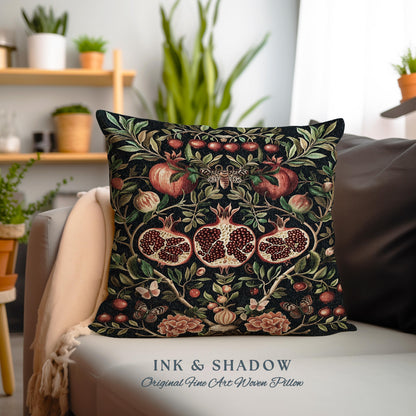 May include: A black throw pillow with a woven design featuring red pomegranates, green leaves, and butterflies. The pillow has the text "INK & SHADOW Original Fine Art Woven Pillow" printed on the bottom.