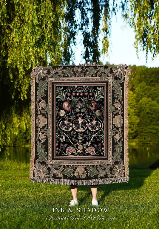 May include: A decorative throw blanket with a detailed pomegranate design in shades of black, green, and pink. The blanket has a fringed edge and features the text "INK & SHADOW Original Fine Art Throws".