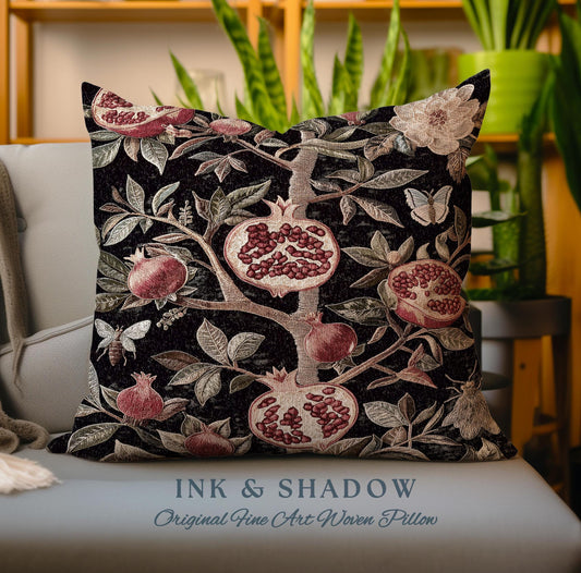 May include: A decorative pillow with a woven design of a pomegranate tree with red pomegranates, green leaves, and a butterfly. The pillow has a black background and the text "INK & SHADOW Original Fine Art Woven Pillow" is printed on the bottom.